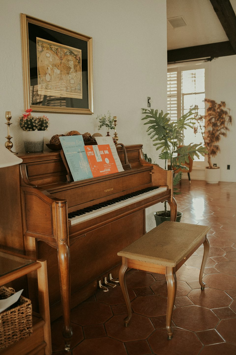 Oude houten piano met bladmuziek staat bij een raam.