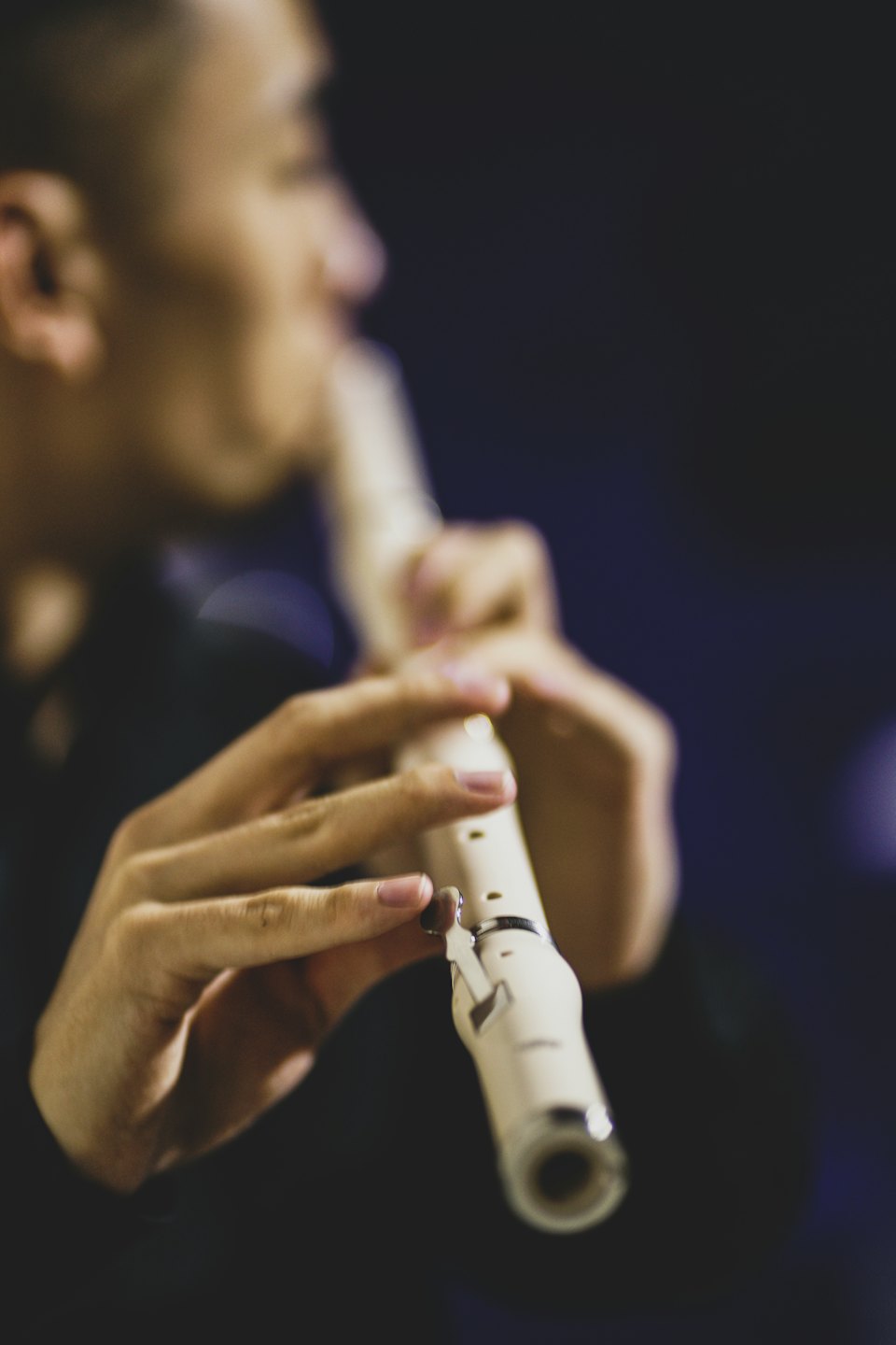 Muzikant bespeelt een crèmekleurige fluit met vingers op de kleppen.